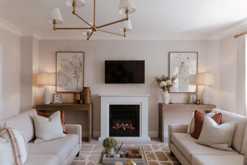 Beautiful neutral sitting room with 2 console tables either side of the fireplace. Brass details on the lights and picture frames